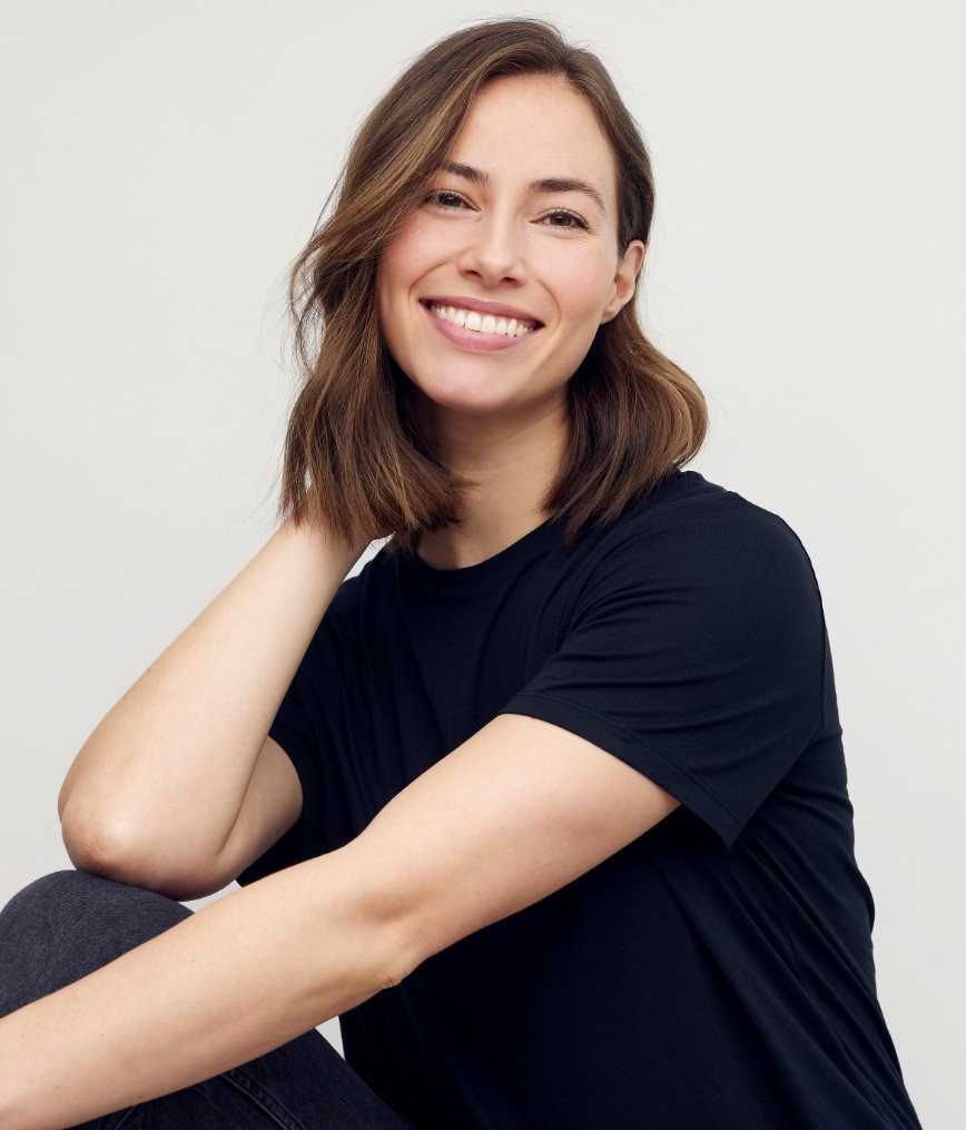 Smiling woman in black tee shirt with her hand behind her head