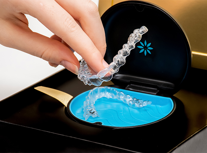 Hand placing an Invisalign aligner in its storage case