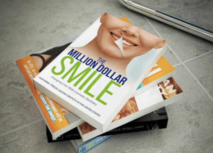 Stack of books with the top one called The Million Dollar Smile Changing Lives with Cosmetic Dentistry