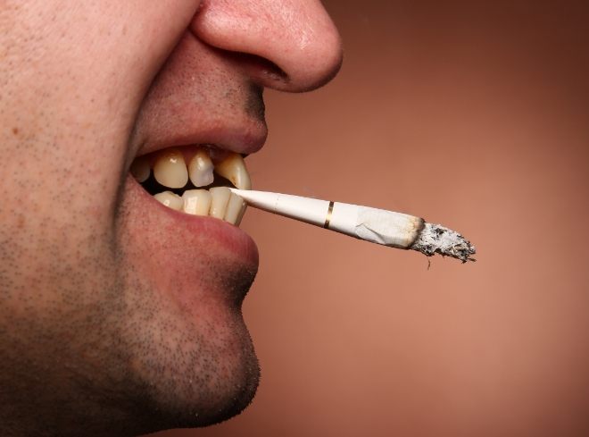 Close up side view of person holding cigarette between their teeth