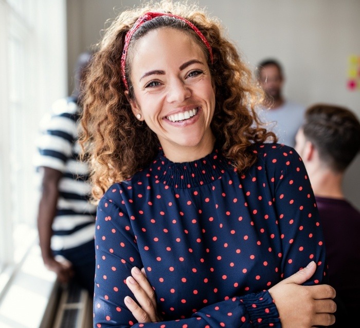 Woman in blue polka dot blouse smiling after cosmetic dental bonding in Houston