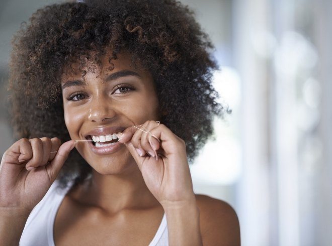 Woman smiling while flossing her teeth