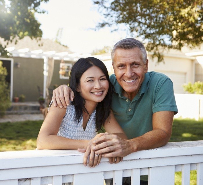 Man and woman in their front yard smiling with dental crowns in Houston