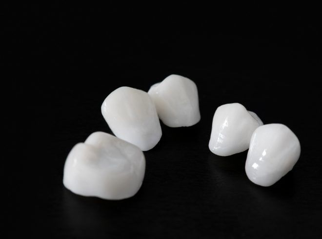 Five dental crowns against black background