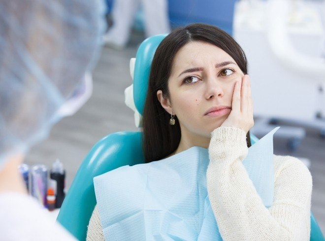 Dental patient holding her cheek in pain