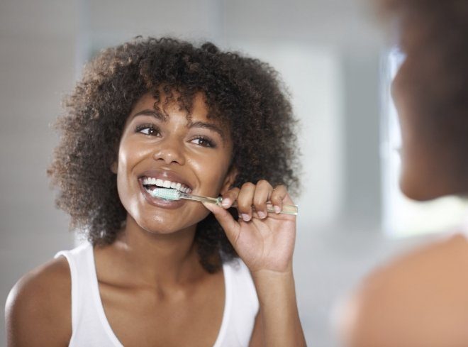 Woman brushing her teeth in front of mirror