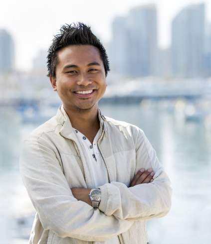 Man in white dress shirt smiling and standing with arms crossed