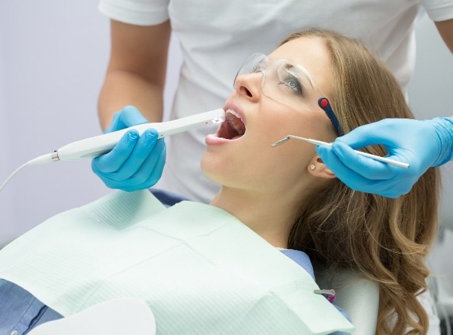 Young woman in dental chair getting intraoral photos of her mouth taken