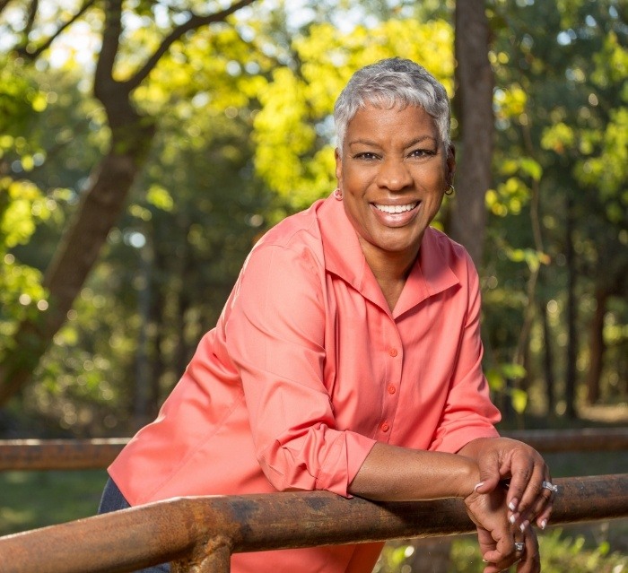 Older woman smiling in front of trees after gum disease treatment in Houston