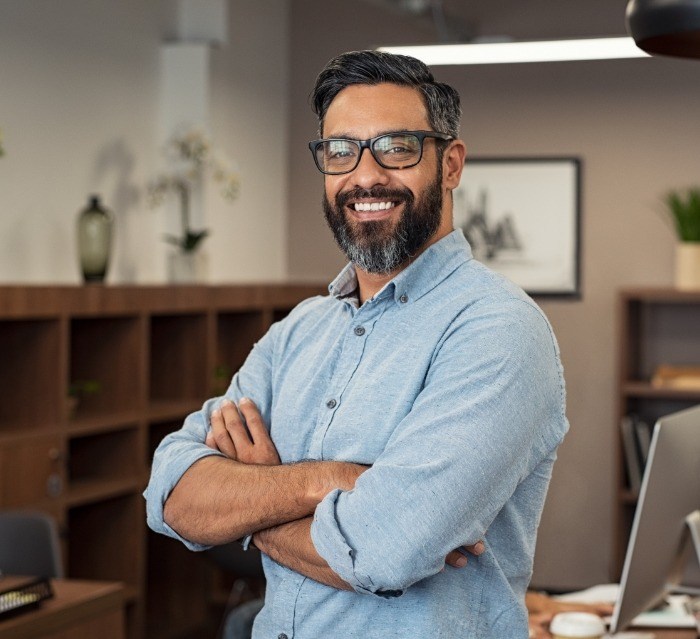 Man in denim shirt smiling after gummy smile correction in Houston