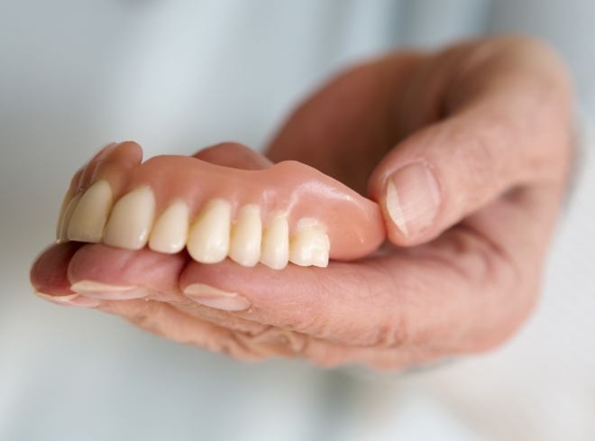 Hand holding a full upper denture