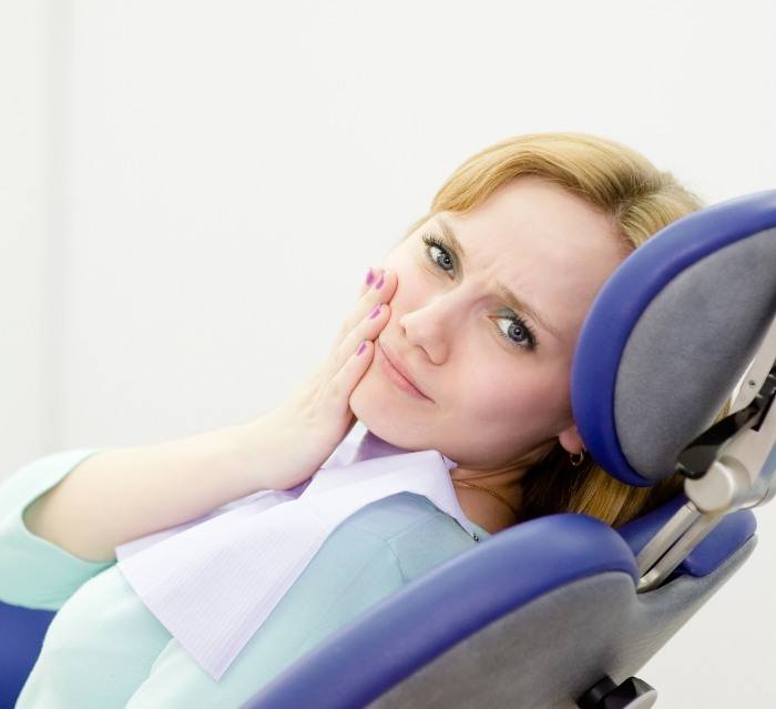 Dental patient holding her cheek in pain before restorative dentistry in Houston