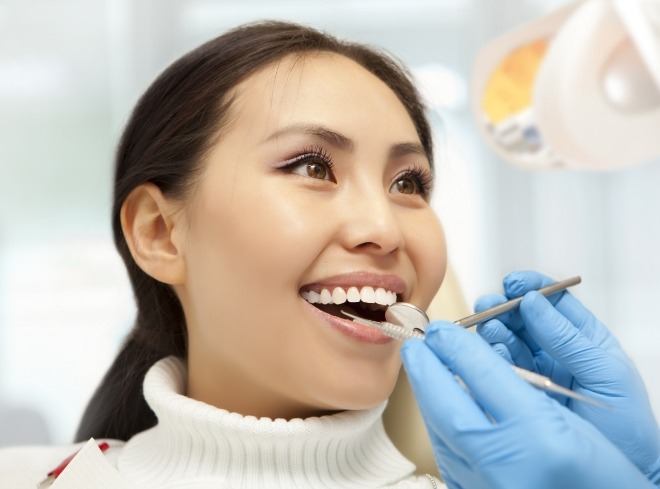 Woman in white sweater having her teeth examined during dental checkup