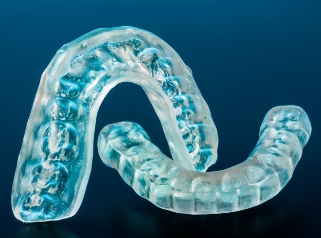 Two clear nightguards for bruxism against dark blue background