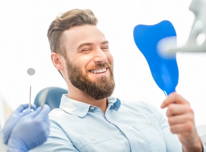 Bearded man seeing his new smile in mirror