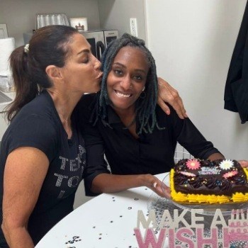 Doctor Alani kissing woman on cheek while they both sit at table with birthday cake