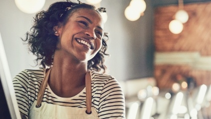 Smiling woman wearing apron in restaurant