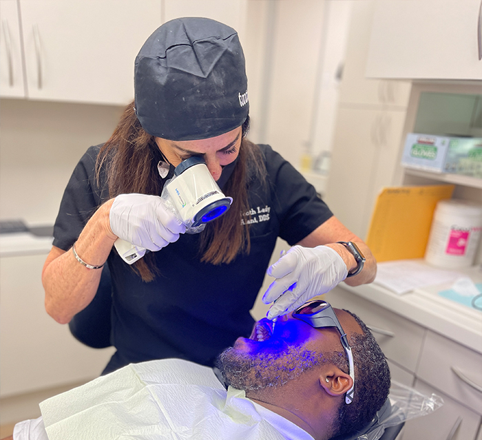 Doctor Alani giving a dental patient an oral cancer screening in Houston