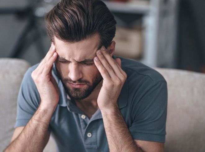 Man holding both of his temples in pain