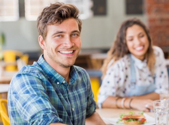 Man in blue plaid shirt smiling at dinner table