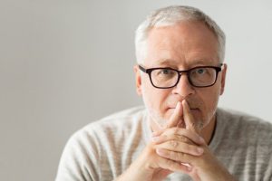 An older man covering his face.