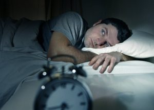 A man laying awaking in bed.