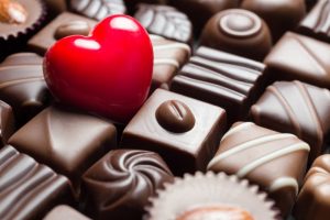 A heart sitting on a box of series of chocolates.