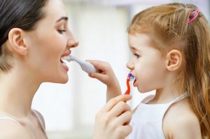 A mother and daughter brushing each other's teeth.