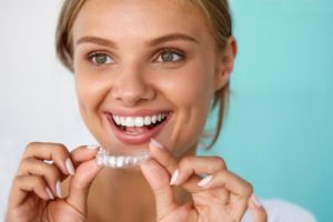 Woman holding clear aligner from a dentist in Uptown Houston.