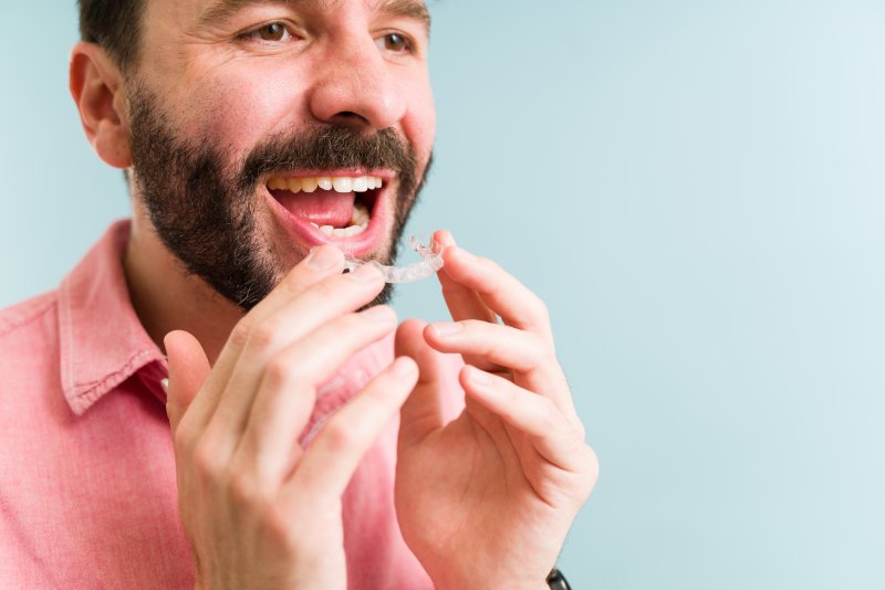 Man holding clear aligner from Invisalign in Uptown Houston