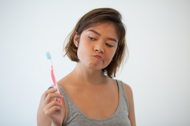 Skeptical woman holding toothbrush 