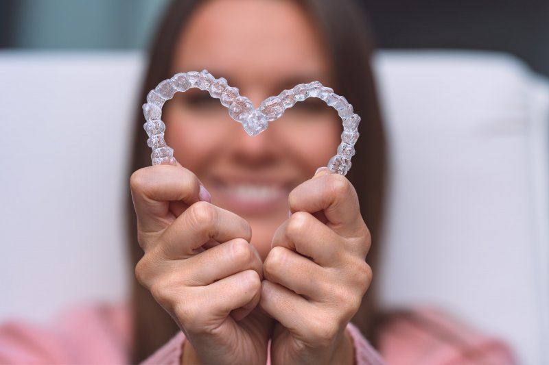 woman holding Invisalign aligners