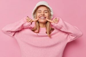 Happy woman smiling and pointing to teeth.